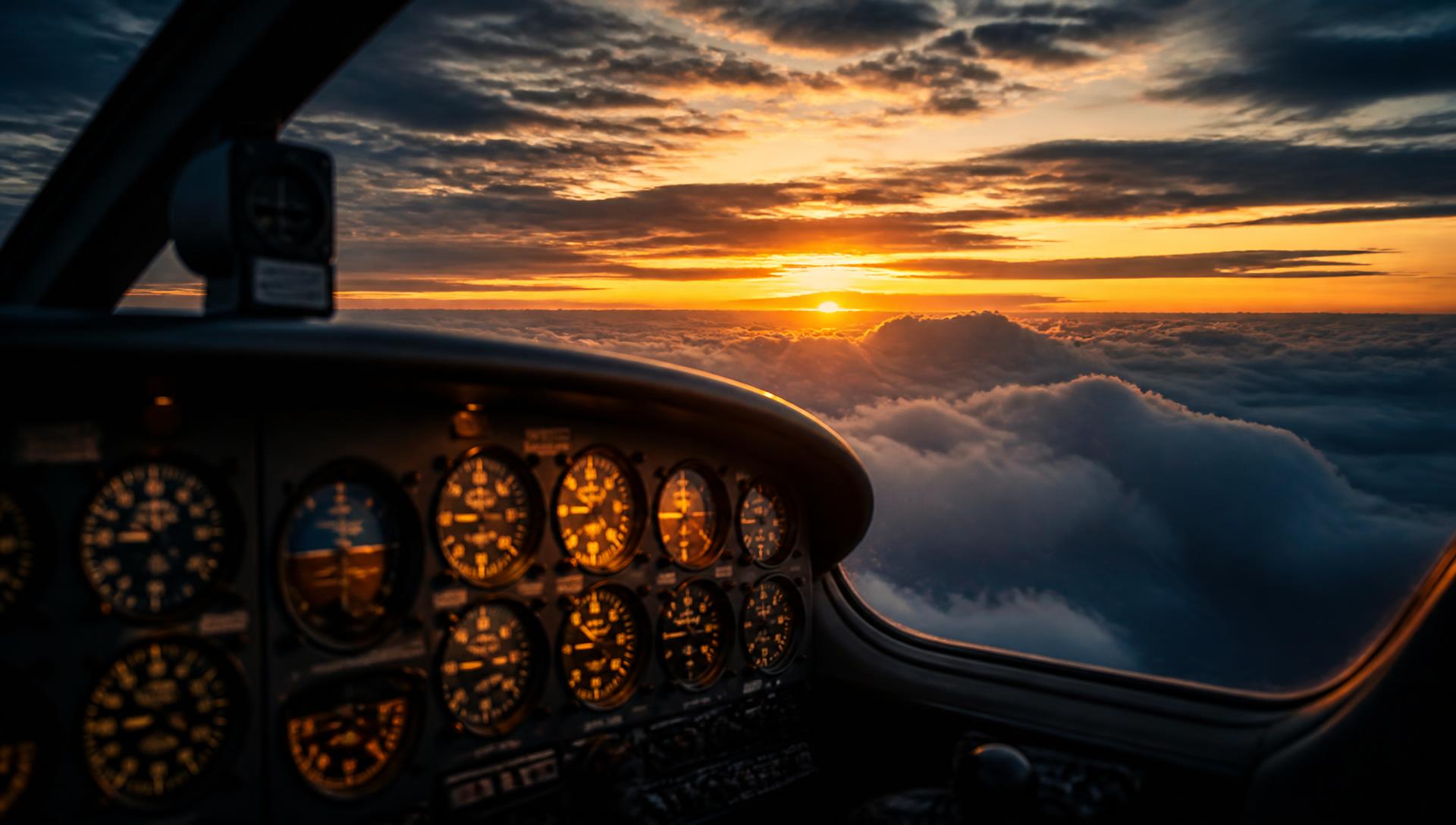 Vista do cockpit de um monomotor acima das nuvens ao pôr do sol